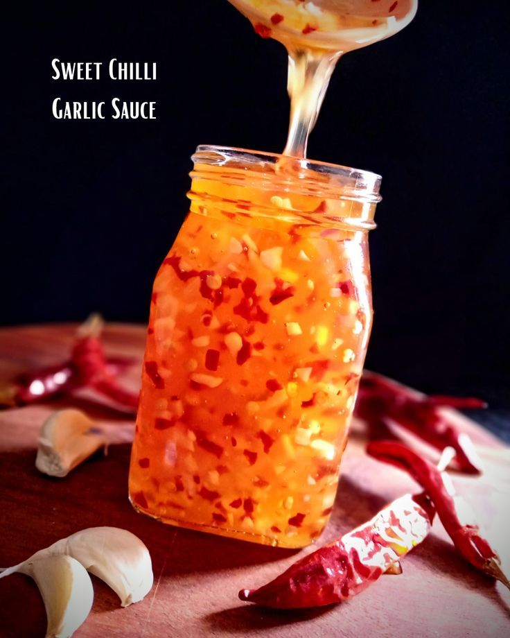 a jar filled with liquid sitting on top of a table next to garlic and peppers