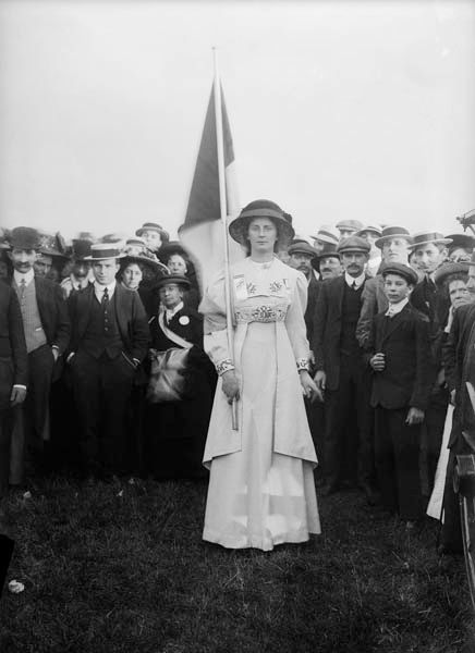 an old black and white photo of a woman holding a flag in front of a crowd