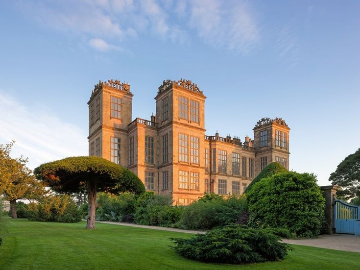 a large building sitting in the middle of a lush green field with lots of trees