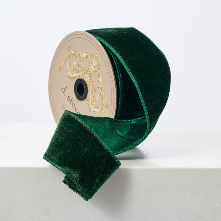 a roll of green velvet ribbon sitting on top of a white surface