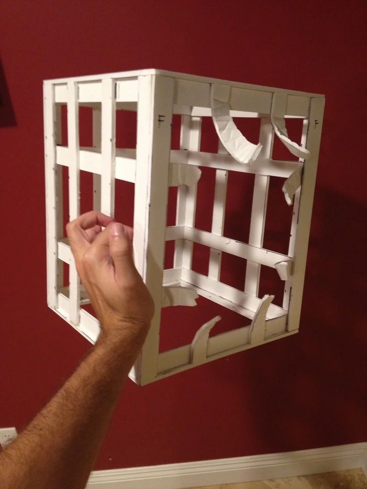 a man is holding up a piece of wood that has been made into a cage