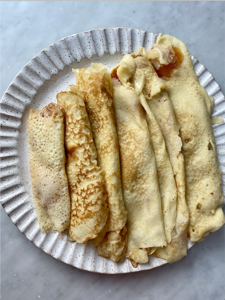 some food is on a paper plate and it looks like pancakes or crepes