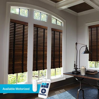 a living room filled with furniture and windows covered in wooden blind shades on top of them