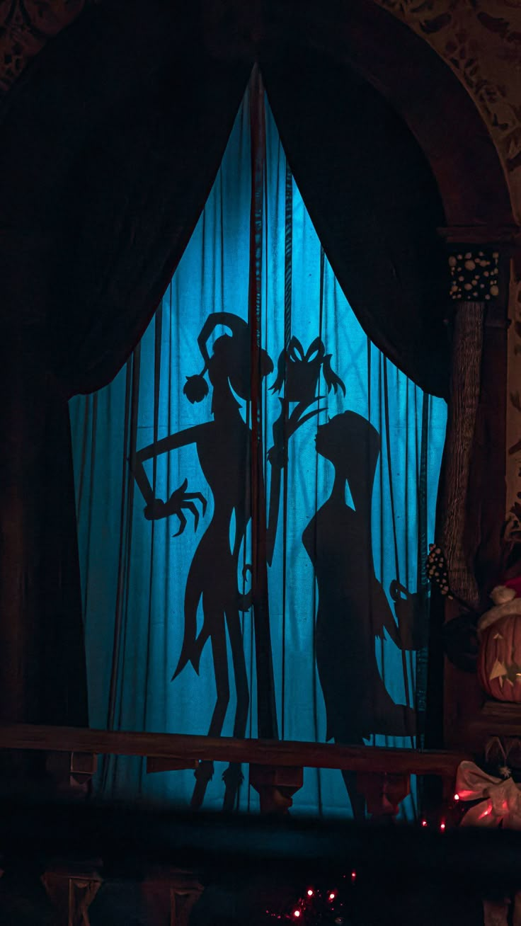 the silhouettes of two people in front of a blue curtain with lights on it