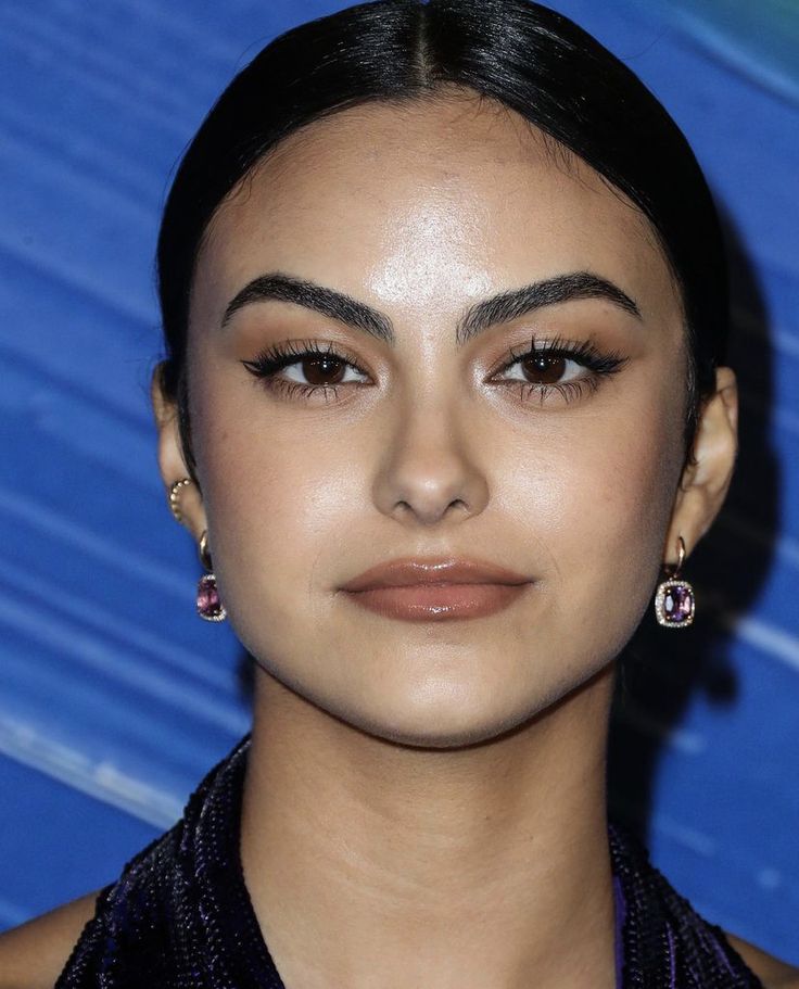 a close up of a person wearing earrings and looking at the camera with an intense look on her face