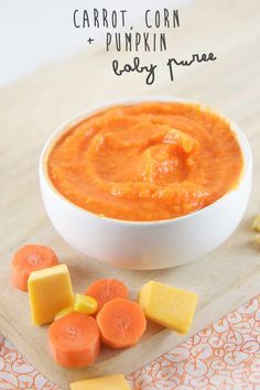 carrot corn and pumpkin baby puree in a white bowl on a wooden cutting board