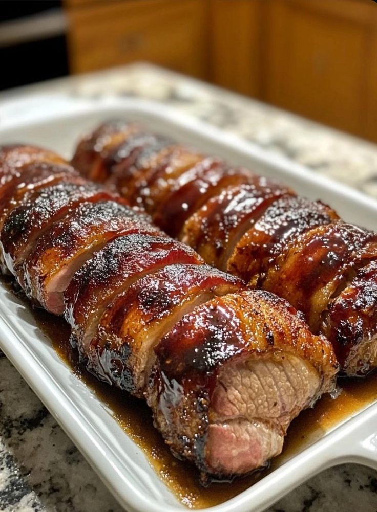 meat wrapped in bbq sauce on a white plate sitting on a marble counter top