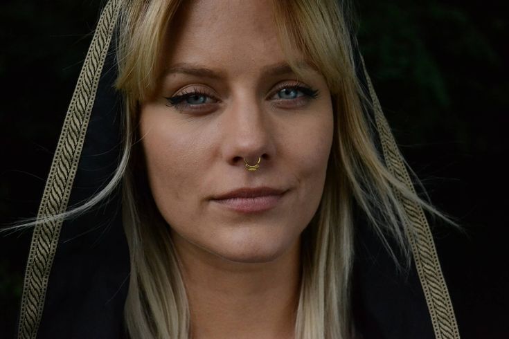 a blonde woman wearing a black hoodie and piercing on her nose is looking at the camera