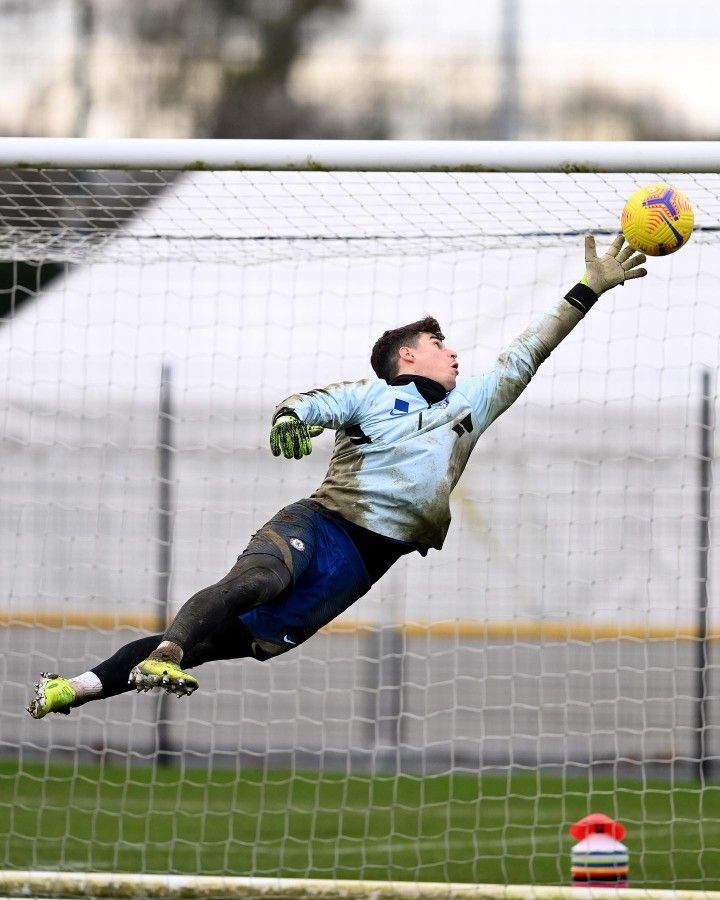 a man diving to catch a soccer ball in front of a goalie's net