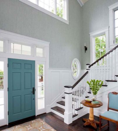 an entryway with blue doors and white trim on the walls, hardwood floors and stairs