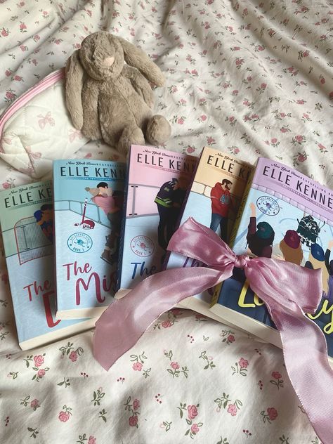 three children's books on a bed with a pink ribbon tied around the book