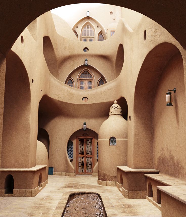 the inside of an adobe building with benches and water feature in the center, surrounded by arches