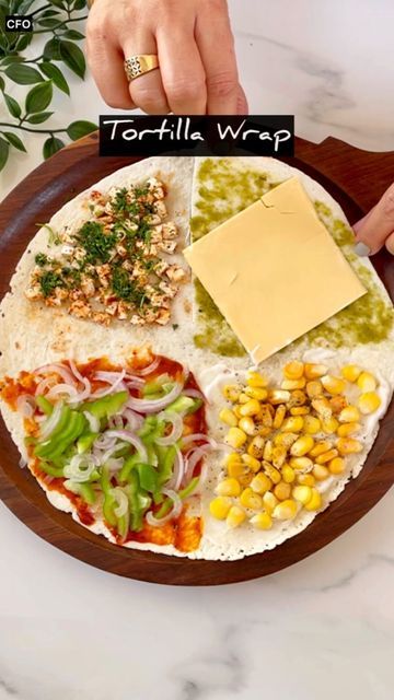 tortilla wrap with toppings on a wooden platter next to a hand holding a piece of cheese