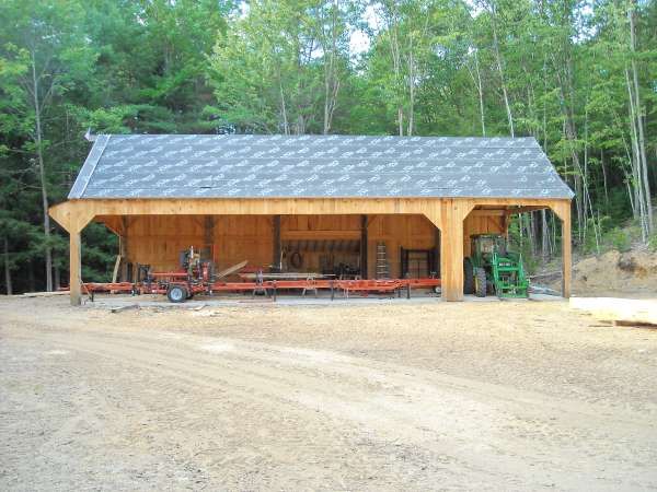 a large wooden building sitting on top of a dirt road in front of some trees