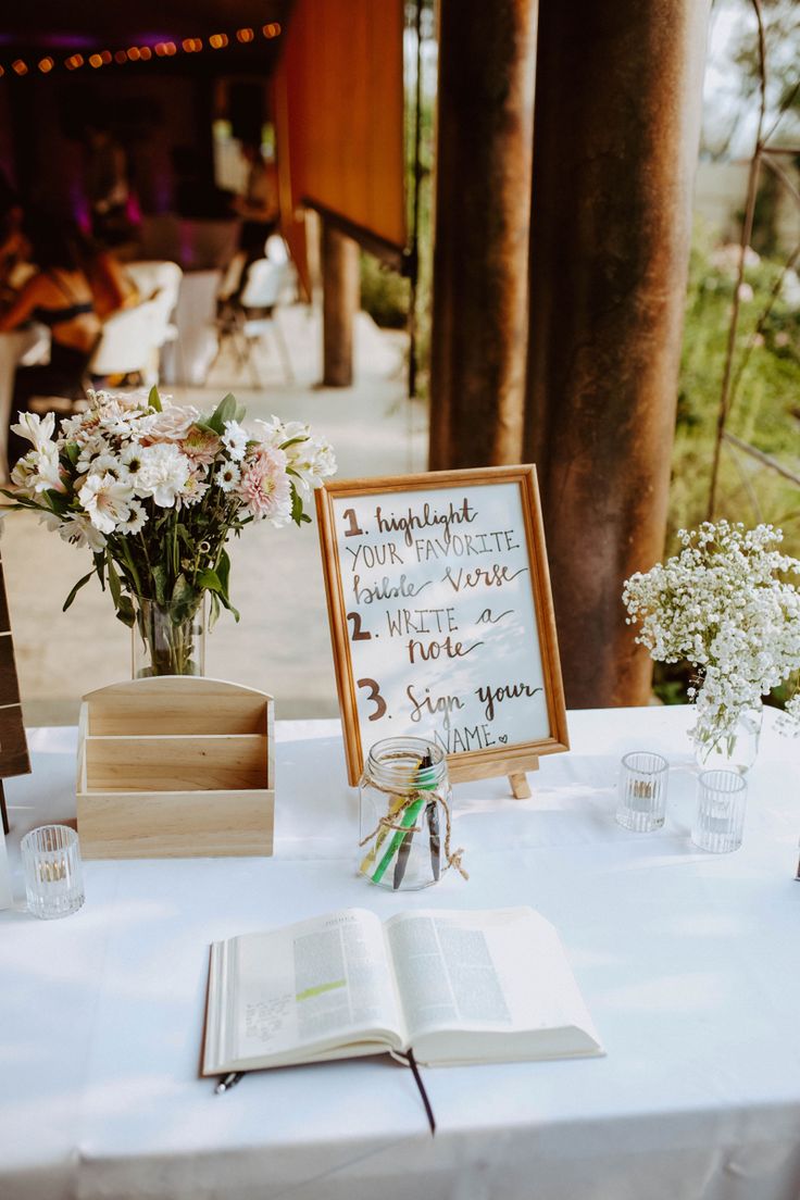 an open book on a table with flowers in vases and a sign that says i love you