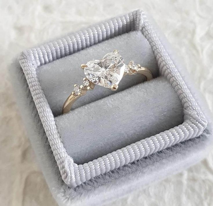 an engagement ring in a box on top of a white furnishe flooring