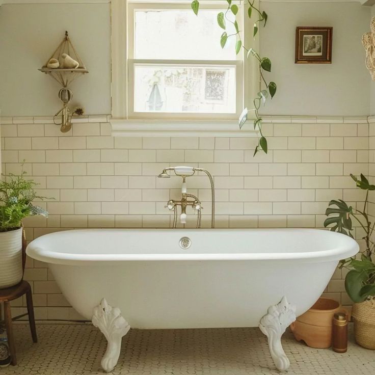 a white bath tub sitting under a window next to a potted plant in a bathroom