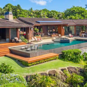 a house with a swimming pool in the middle of it, surrounded by lush green trees