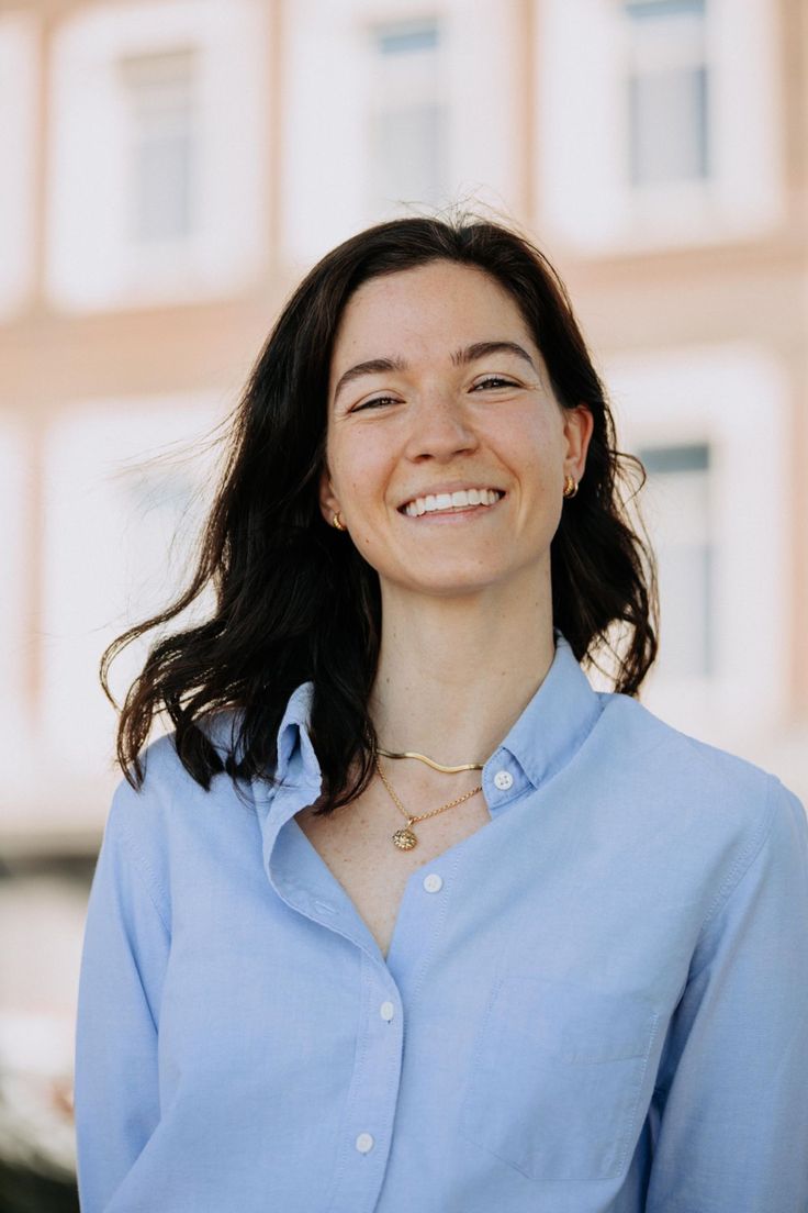 a woman smiling and wearing a blue shirt