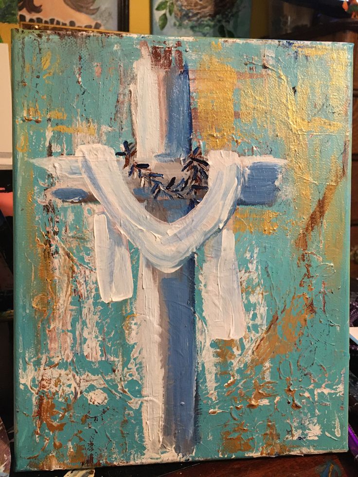 a painting of a cross with blue and white paint on it, sitting on a table