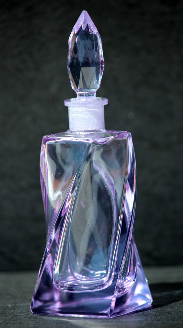 a purple glass perfume bottle sitting on top of a table