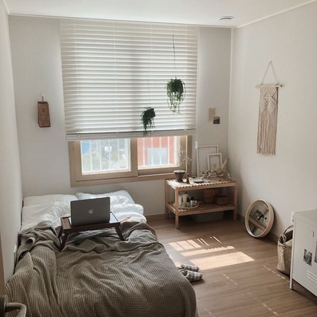 a laptop computer sitting on top of a bed in a bedroom next to a window