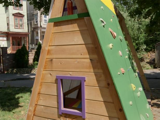 a child's play house made out of wood with a slide and climbing wall