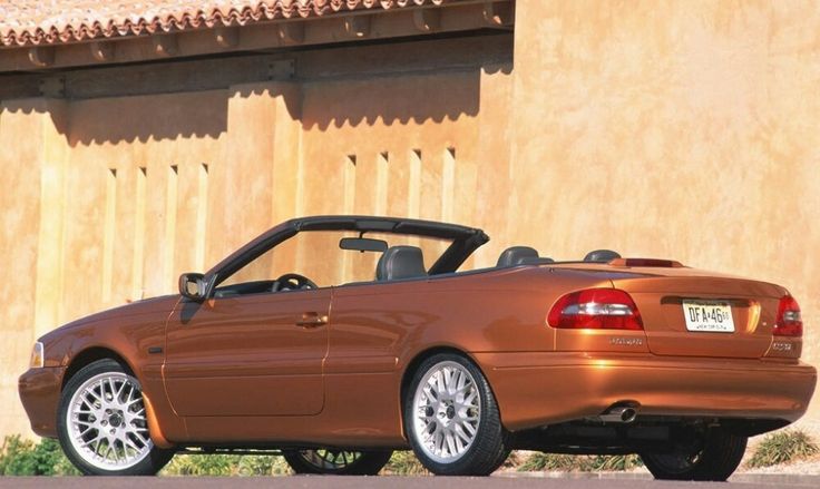 an orange convertible car parked in front of a building