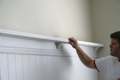 a man is painting the trim on a wall with white paint and an orange marker