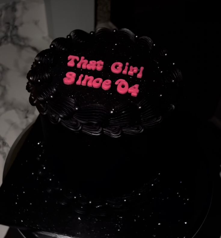 a black cake with pink writing on it