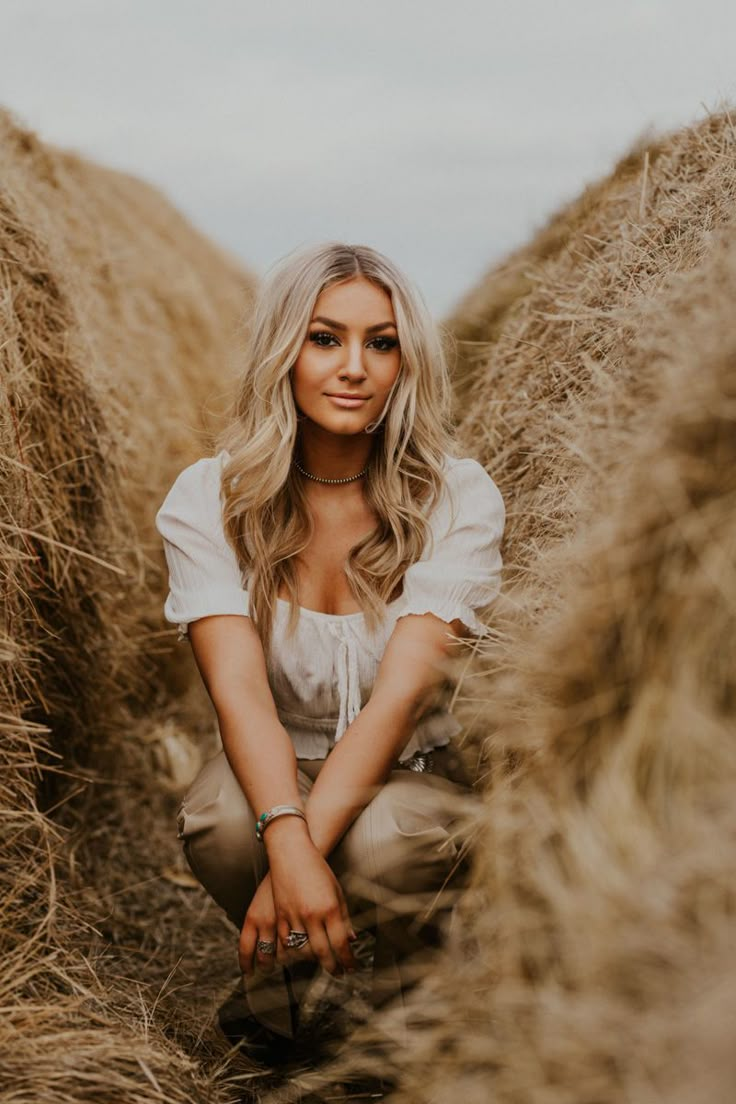 a woman sitting in the middle of some hay