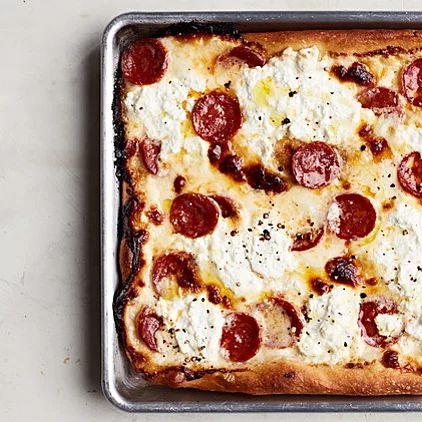 a square pepperoni and cheese pizza sitting on top of a pan