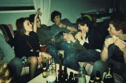 black and white photograph of people sitting on a couch with beer bottles in front of them