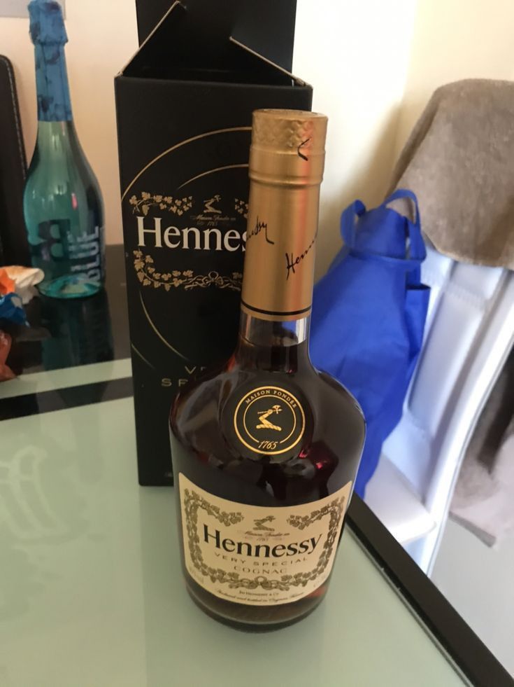 a bottle of hennesy is sitting on a table next to a blue bag