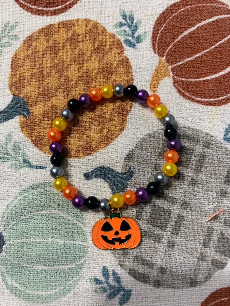 a beaded bracelet with an orange and black jack - o'- lantern charm