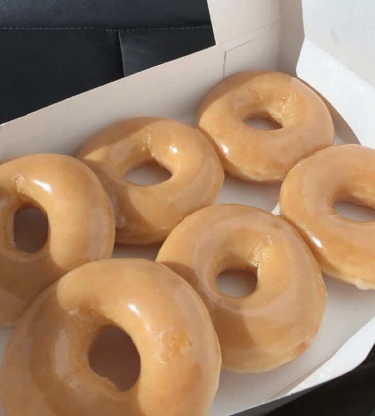 six glazed donuts in a white box on a table