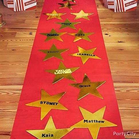 a red table runner with gold stars on it and some popcorn boxes in the background