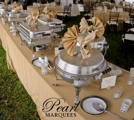 a table topped with lots of silver trays covered in bowknots and plates