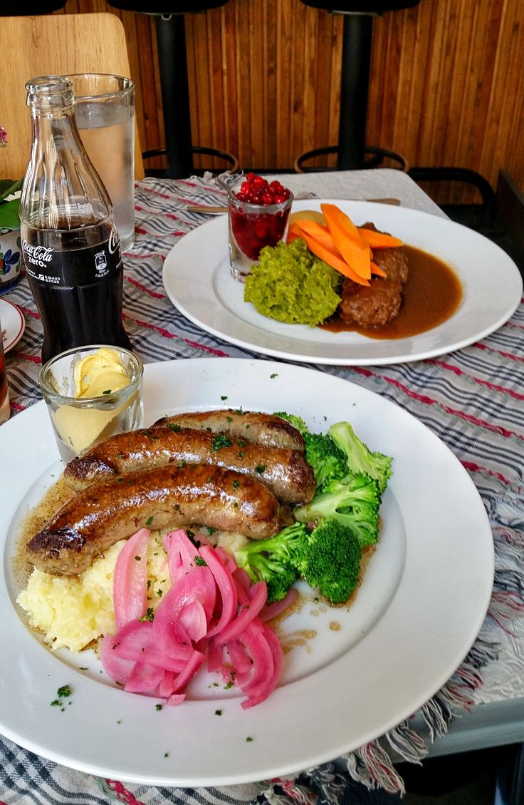 two plates with sausages, mashed potatoes and broccoli are on the table