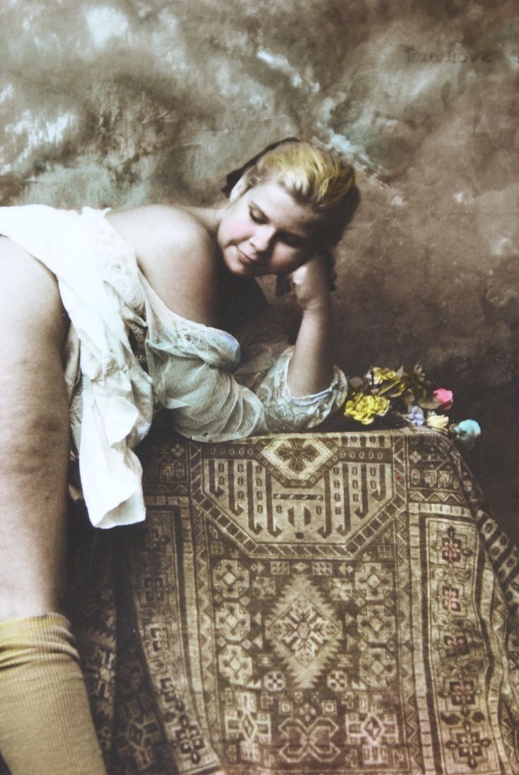 a woman sitting on top of a rug with her legs crossed and head resting on her hand