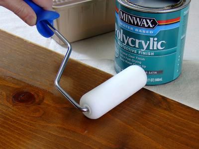 a person using a paint roller to paint wood