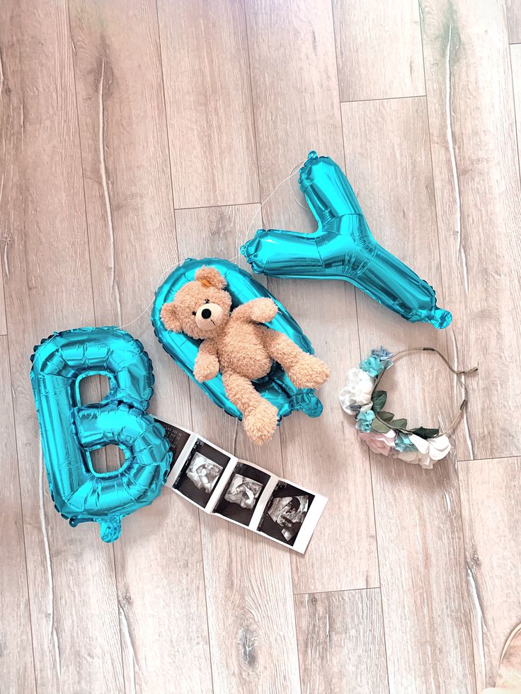 a baby's first birthday with balloons and teddy bear on the floor next to it