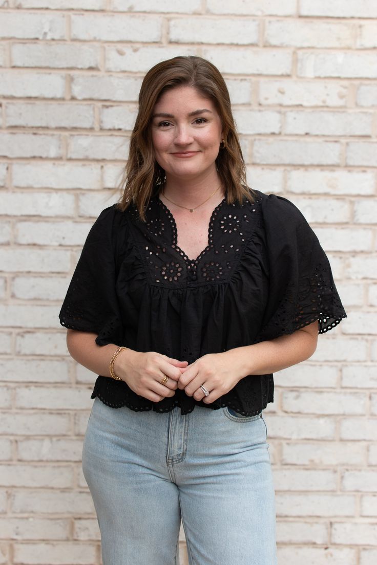 Elevate your wardrobe with the Kasey Eyelet Top, a charming blend of delicate details and effortless style. This top features intricate eyelet patterns that add a touch of femininity, while the flutter sleeves provide a soft, romantic flair. The V neckline, adorned with subtle button details, creates a flattering silhouette, and the scalloped hem adds a hint of whimsy. Crafted from a breathable, cotton fabric, the Kasey Eyelet Top is perfect for transitioning into fall. We love pairing it with w Feminine V-neck Crochet Top For Spring, Feminine Short Sleeve Eyelet Blouse, Chic V-neck Blouse With Crochet Trim, Feminine Crochet Top With Lace Trim And V-neck, Feminine Crochet V-neck Top With Lace Trim, Summer Eyelet V-neck Blouse, Summer V-neck Eyelet Blouse, Chic V-neck Top With Crochet Trim, Feminine V-neck Tops With Lace Collar