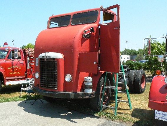 an old red truck parked next to other trucks