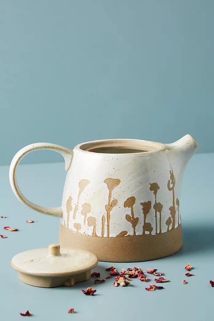 a ceramic tea pot sitting on top of a table next to confetti flakes