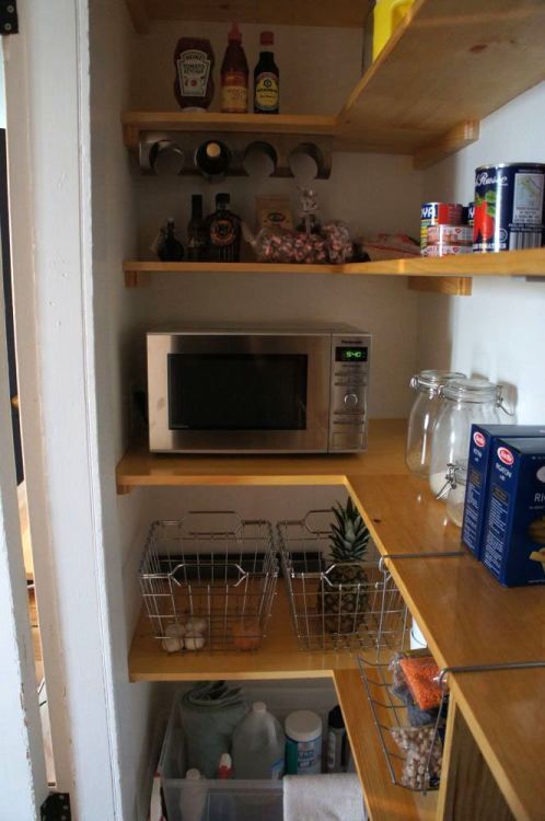 a microwave and other items in a small kitchen area with open shelve on the wall