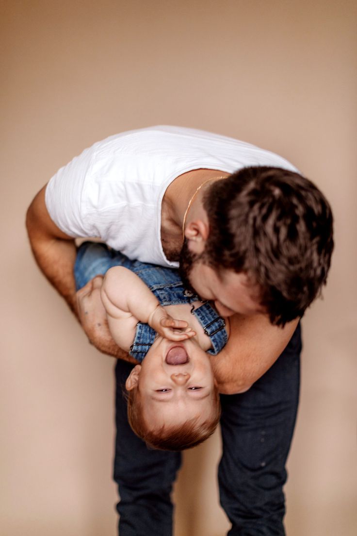 a man holding a baby up to his face while he holds it in the air