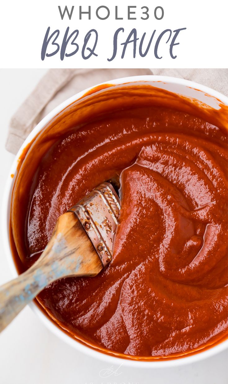 a white bowl filled with bbq sauce and a wooden spoon in the bottom right corner