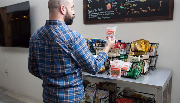 a man standing in front of a table with food on it and a menu behind him