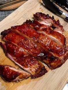 the meat is sliced up and ready to be served on the cutting board with utensils